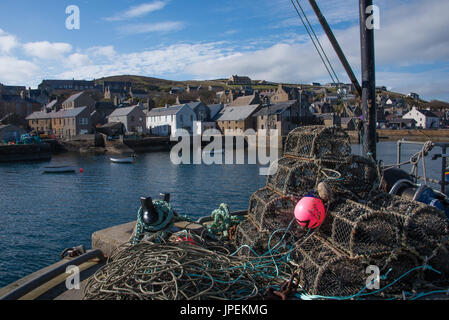 Il Molo di Ponente nel porto di Stromness è disseminato di fihing attrezzature - reti, casse di pesce, vecchie funi e altri paraphernalia Foto Stock