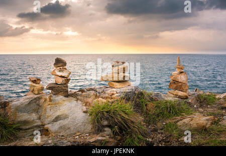 Pietre impilate su una spiaggia in Thailandia al tramonto Foto Stock