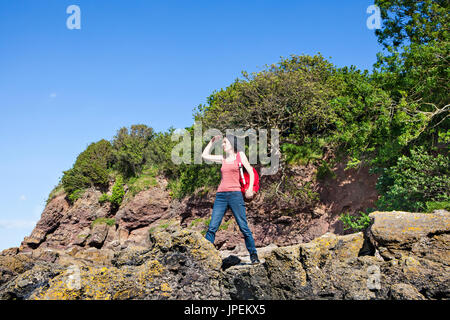 Donna in piedi sulle rocce guardando a vista Foto Stock