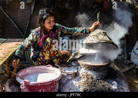 Lago Inle, MYANMAR - 15 febbraio 2014: giovane signora birmano la cottura del riso allevati Foto Stock