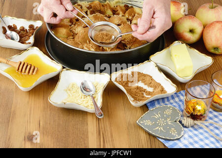 La cottura della torta di mele con ingredienti intorno come il miele di mandorle e cannella. Foto Stock