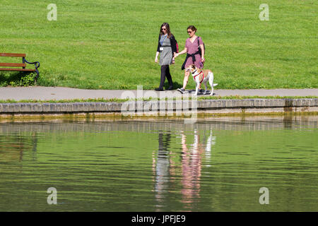 Abington Park, Northampton, meteo, 1 agosto 2017. Il sole di questa mattina con la luce delle nuvole e ora di nuovo la previsione per il giorno. 2 amiche a piedi un cane intorno al lago in barca sotto il sole. Credito: Keith J Smith./Alamy Live News Foto Stock