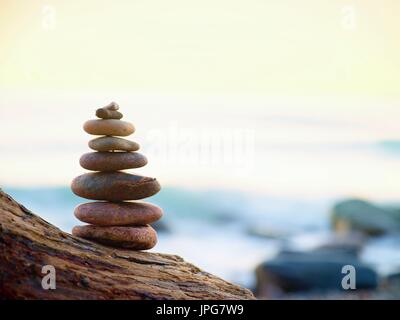 Equilibrato piramide di pietra sulla riva del mare, le onde in background Foto Stock