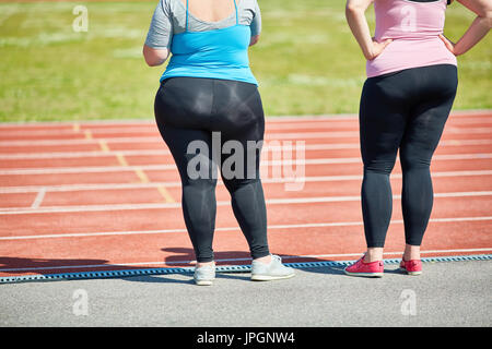 Vista posteriore del basso-sezione di grasso le giovani donne in piedi alla stadio da race track Foto Stock