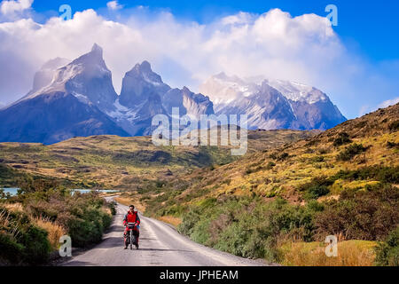 Uomo su una bicicletta sulla strada che conduce alla suggestiva Cuernos del Paine picchi nel Parco Nazionale Torres del Paine, Cile, Sud America Foto Stock