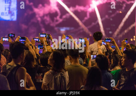 La folla dei popoli asiatici la registrazione video fuochi d'artificio su telefoni cellulari invece di guardare direttamente. Al ventesimo anniversario di Hong Kong che tornano in Cina. Foto Stock