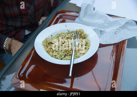 Giovani intraprendenti boy mangiare ramen a pranzo. Egli è in appoggio un mentre dal lavoro per raccogliere energie. Foto Stock