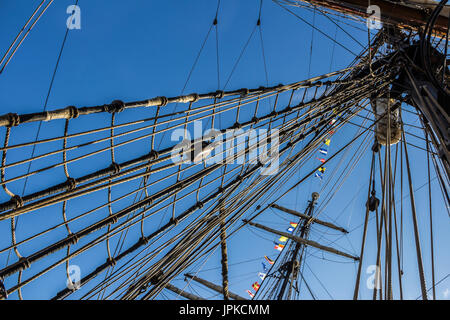 Parte nautico di una barca o un grande vecchio veliero con cordicelle, rigging, vela, piloni, nodi, segnale bandiere blu cielo Foto Stock