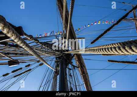 Parte nautico di una barca o un grande vecchio veliero con cordicelle, rigging, vela, piloni, nodi, segnale bandiere blu cielo Foto Stock