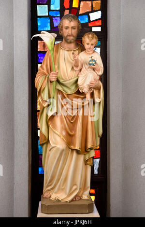 Statua di San Giuseppe padre adottivo holding figlio Bambino Gesù e gigli a vetrata di Saint Roch della cattolica Chiesa di Toronto in Canada Foto Stock