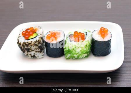 Rotolo di sushi di pezzi sul piatto di portata in ceramica bianca con caviale Foto Stock