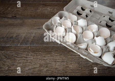 Rotture di gusci delle uova in una scatola di cartone su un asse di legno scheda con spazio per la copia o lo spazio di testo Foto Stock