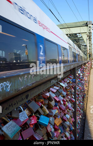 Colonia/Germania - 10 Maggio 2017: velocità del treno lungo il ponte di Hohenzollern con molte colorate amore si blocca Foto Stock