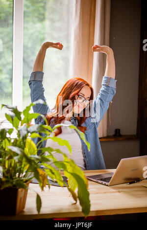 Libero professionista donna stretching mani fino al luogo di lavoro. Home ufficio di giovane donna che lavora in modalità remota. Tonica immagine. Foto Stock