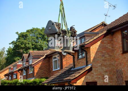 E fuori lei proviene, un grande Henry Milnes tornio viene sollevato dalla parte posteriore di una proprietà fuori ed espressiva attraverso una intercapedine tra le case di attesa autocarro per il trasporto Foto Stock
