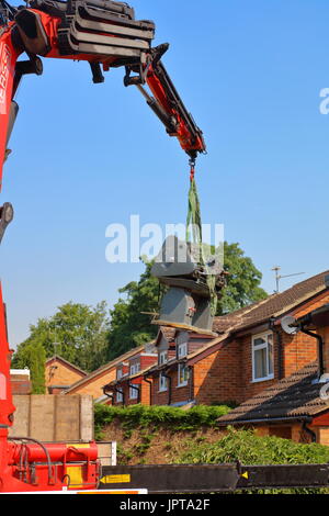 E fuori lei proviene, un grande Henry Milnes tornio viene sollevato dalla parte posteriore di una proprietà fuori ed espressiva attraverso una intercapedine tra le case di attesa autocarro per il trasporto Foto Stock