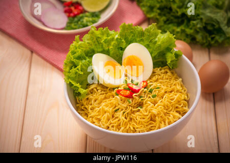 Tagliatelle istante nella ciotola con le verdure e uova sode o su uno sfondo di legno Foto Stock