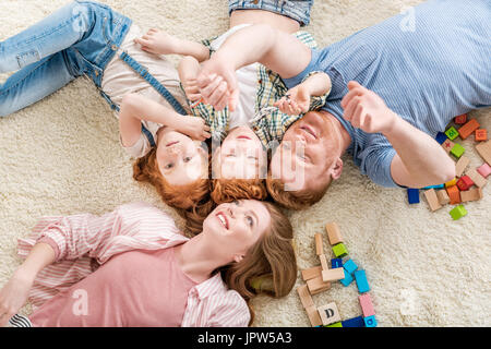 Vista superiore della famiglia felice sdraiato sul pavimento, big family portrait concept Foto Stock