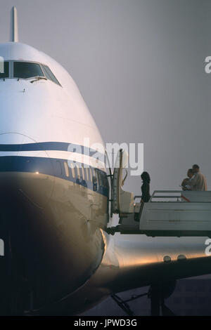 Una donna sola l'imbarco dei passeggeri fino airstairs di un telecomando-parcheggiato Air China Boeing 747-400 Foto Stock