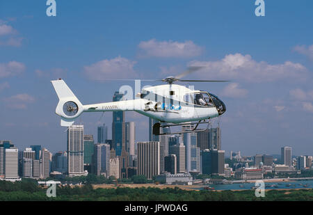 Eurocopter EC-120 prototipo Colibri battenti lungo il tragitto con il centro di Singapore il distretto centrale degli affari di grattacieli dietro Foto Stock