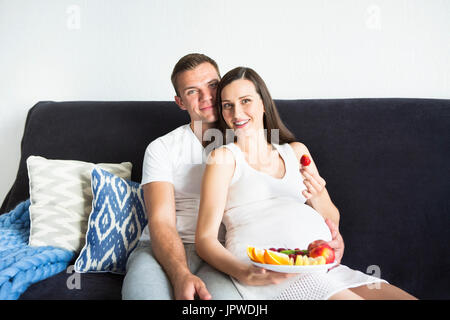 Giovani incinte sorridente bella donna e uomo con frutta Foto Stock