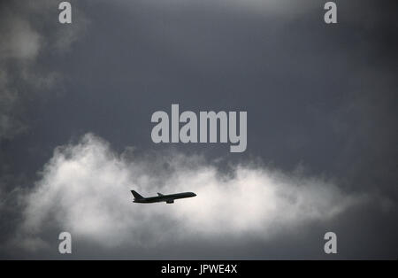 Boeing 757-200 salendo lungo il tragitto tra le nuvole scure Foto Stock