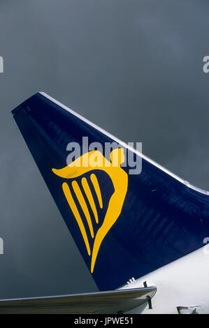 Tail-fin con il logo di un Ryanair Boeing 737-800 contro un cielo nuvoloso scuro Foto Stock