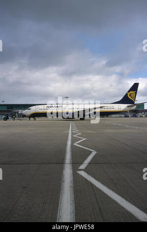 Ryanair Boeing 737-800 essendo spinto-indietro di un rimorchiatore da supporto di stazionamento e grembiule iscrizioni in primo piano e le nuvole sopra Foto Stock