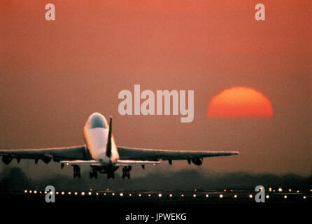 Boeing 747-200 il decollo al tramonto dalla pista con luci accese Foto Stock