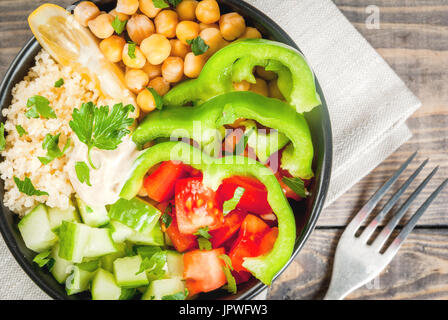 Mangiare sano, la dieta. Vegetariano buddha vegetale bowl - cuscus (quinoa), ceci, pomodori, zucchini (cetrioli), pepe, hummus, limone e verdi Foto Stock