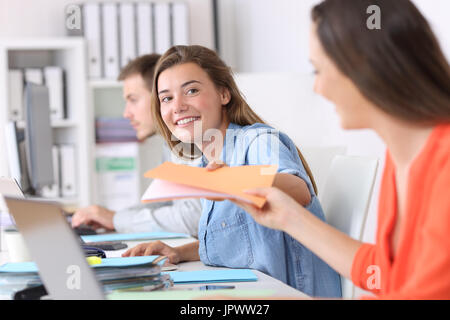 Felice dando dei dipendenti di una cartella di documenti a un collega in ufficio Foto Stock