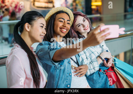 Sorridente giovani donne con le borse della spesa tenendo selfie, giovani ragazze il concetto di shopping Foto Stock