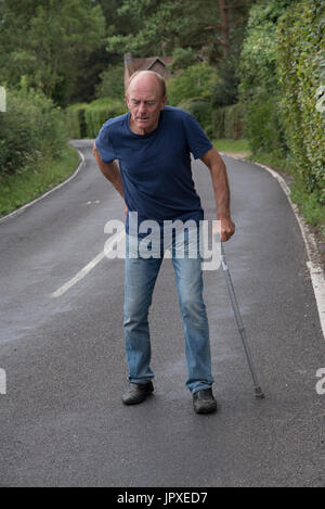 Anziani disabili uomo con dolore alla schiena con un bastone da passeggio Foto Stock