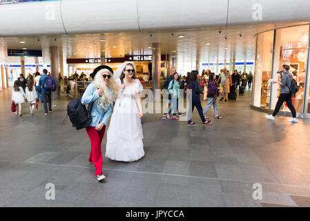 Due giovani donne in abiti eleganti che camminano attraverso King's Cross Station con altri pendolari, Londra, Regno Unito. 3rd agosto, 2017. Foto Stock