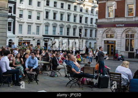 Covent Garden London Square Place NatWest Bank guarda la folla che mangia fuori cibo e bevande, sedie a sdraio, archi ad arco intelligenti, vecchie finestre Foto Stock