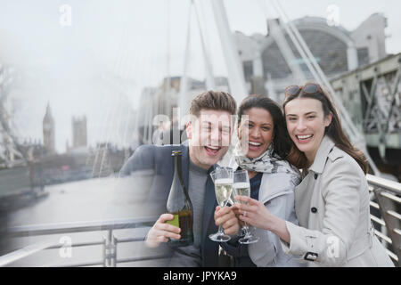 Ritratto aziendale entusiasta persone celebrando, tostatura champagne sul ponte urbano, London, Regno Unito Foto Stock