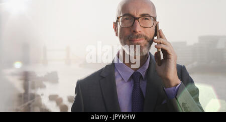 Ritratto di imprenditore serio parlando al cellulare sul ponte urbano, London, Regno Unito Foto Stock