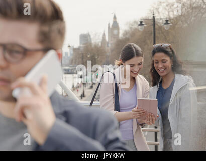 Amici di sesso femminile con tavoletta digitale sul ponte urbano, London, Regno Unito Foto Stock