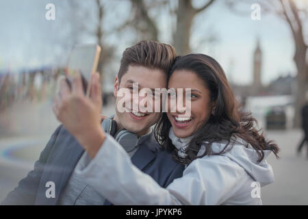 Coppia sorridente tenendo selfie con la fotocamera del telefono nel parco urbano Foto Stock