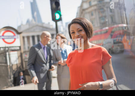 Ritratto sorridente imprenditrice sulla soleggiata città urban Street, Londra, Regno Unito Foto Stock