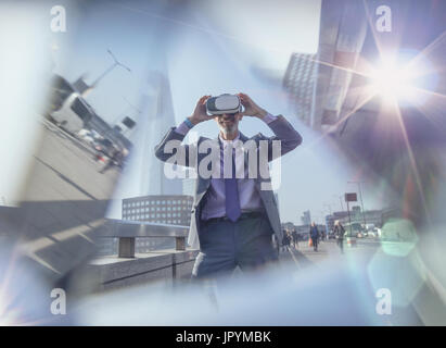 Imprenditore utilizzando la realtà virtuale occhiali simulatore su strada urbana, London, Regno Unito Foto Stock