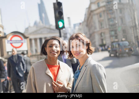 Ritratto sorridente, fiduciosi imprenditrici sulla soleggiata città urban Street, Londra, Regno Unito Foto Stock