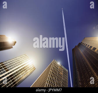 Aeroplano e vapor trail nel cielo blu sopra highrise edifici, concetto di viaggio Foto Stock