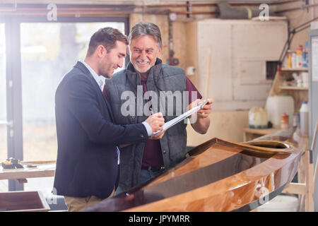 Maschio il cliente firma la documentazione per legno finito kayak in officina Foto Stock