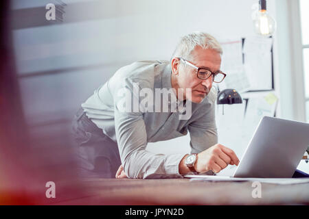 Grave, focalizzata imprenditore lavora al computer portatile in ufficio Foto Stock