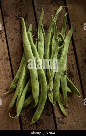 Ancora vita close up fresche, organico, sano, rustico, sporco verde fagiolo baccello su legno Foto Stock