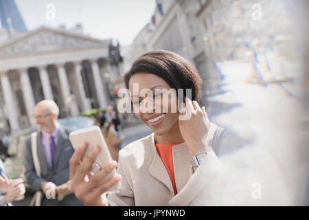 Sorridente imprenditrice tenendo selfie con la fotocamera del telefono, London, Regno Unito Foto Stock