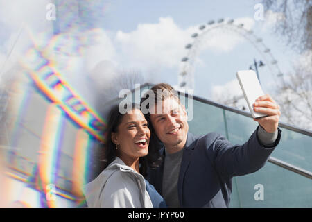 Coppia sorridente turisti tenendo selfie vicino al Millennium Wheel, London, Regno Unito Foto Stock