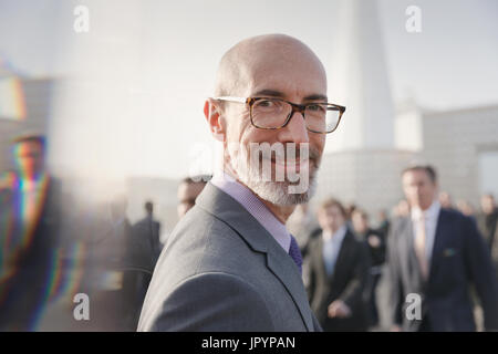 Ritratto sorridente, imprenditore fiducioso su occupato marciapiede urbano, London, Regno Unito Foto Stock