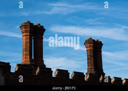 Close-up dettaglio di mattoni rossi camini e comignoli sulla parete esterna di Tudor edificio di architettura Foto Stock